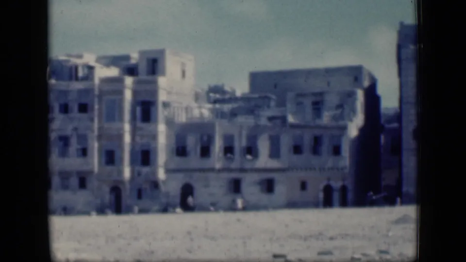 1946 Cairo exterior frame showing a broad pale building complex, arched openings, dark windows, and an empty open plain.