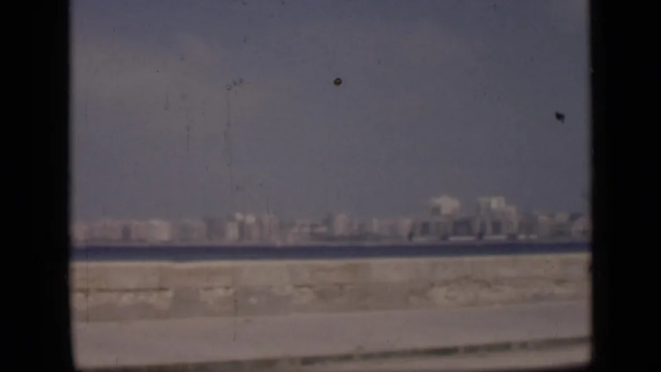 Distant Cairo waterfront view from 1946 metadata, with low buildings across water and dark vertical film-frame edges.