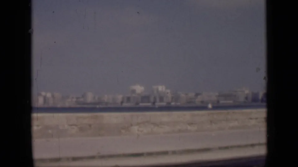 1946 Cairo waterside cityscape frame with far buildings, a dark water band, pale embankment, and pronounced 8mm border edges.