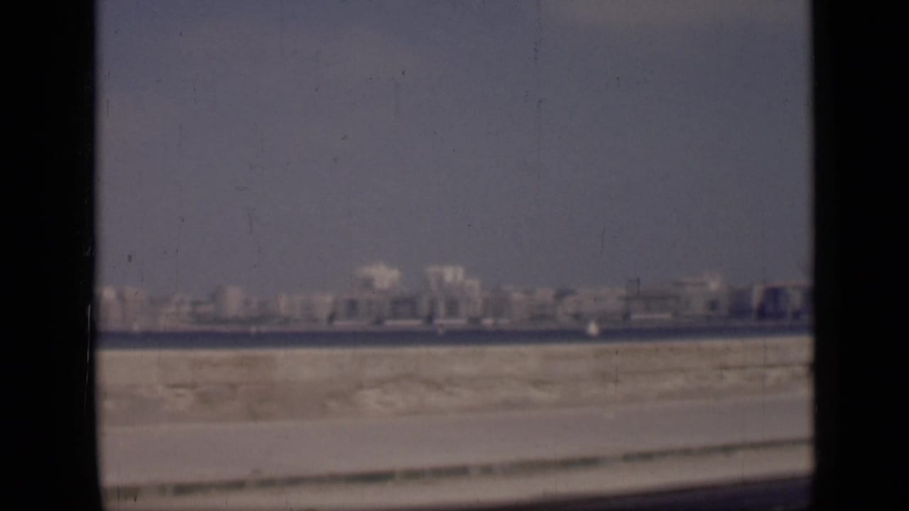 1946 Cairo footage looking across water toward a hazy skyline, with a sandy roadside foreground and visible film gate edges.