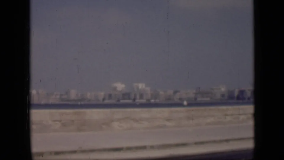 1946 Cairo footage looking across water toward a hazy skyline, with a sandy roadside foreground and visible film gate edges.