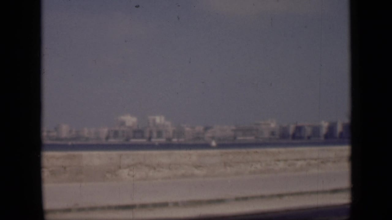 1946 Cairo waterfront view with a low skyline across the water and sandy roadside foreground, framed by dark 8mm borders.