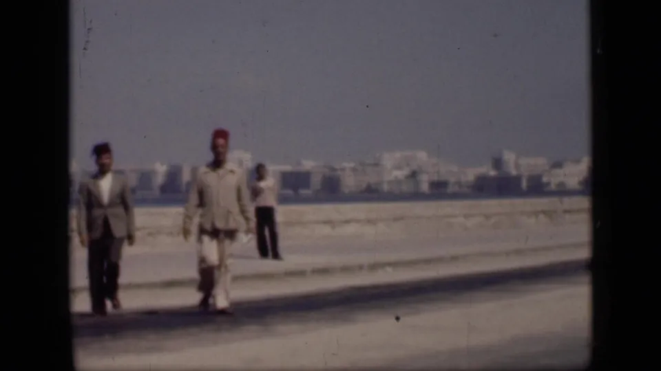 1946 Cairo street view showing three men walking toward the camera near the waterfront, including one man in a red fez.
