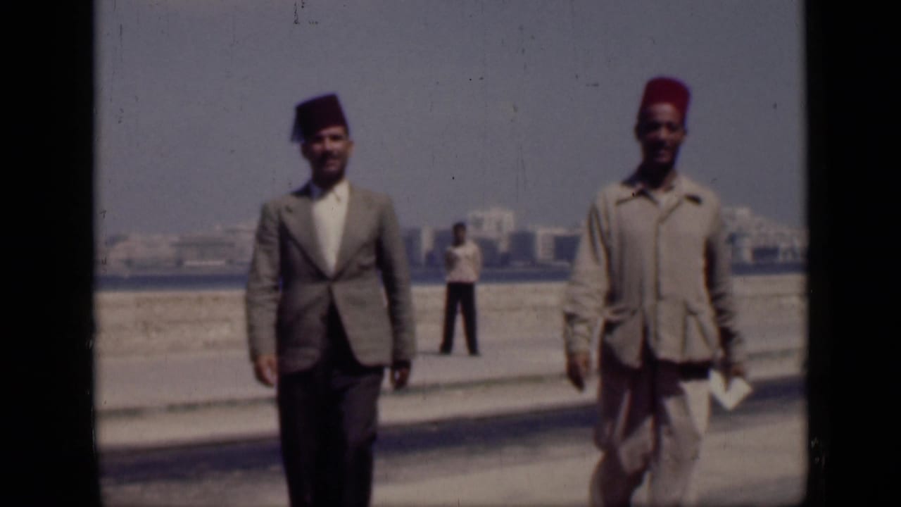 1946 Cairo home-movie frame showing two men in fez hats walking toward the camera, with another person standing in the background.