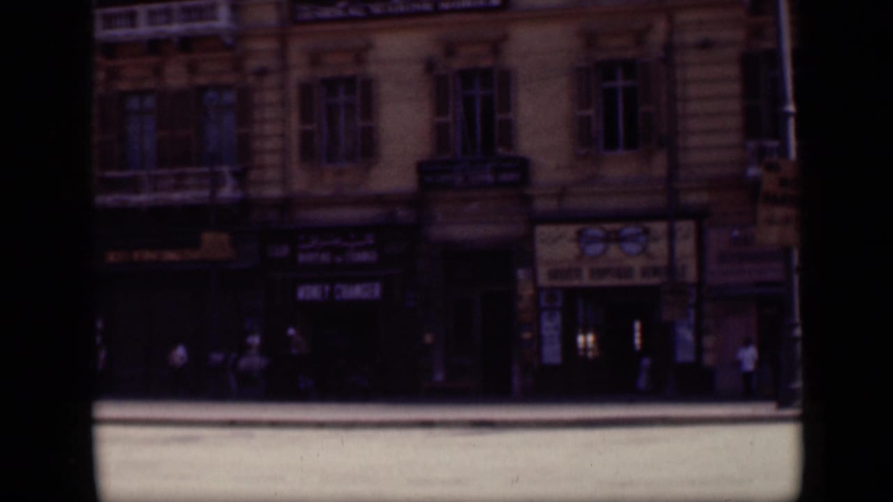 1946 Cairo street view with multi-story building facades, shop signs, and small figures walking near the storefronts.