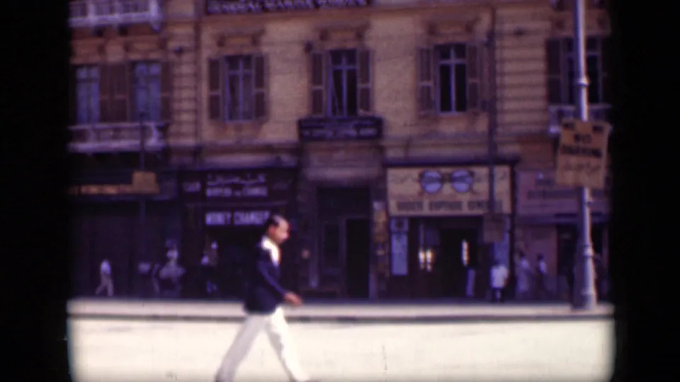 1946 Cairo street frame with a man in a dark jacket walking across the foreground before storefronts and visible signs.