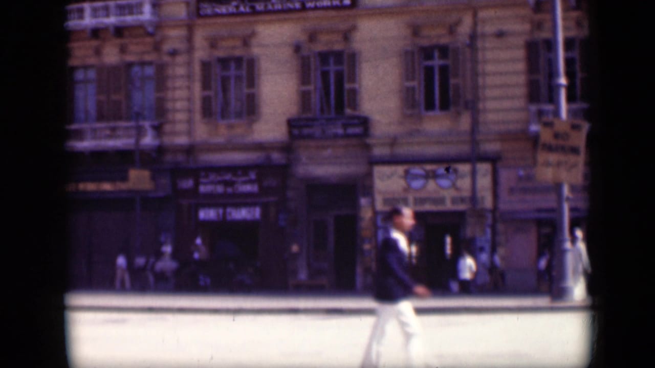1946 Cairo street view with a man crossing in front of storefront signs and a multi-story facade.