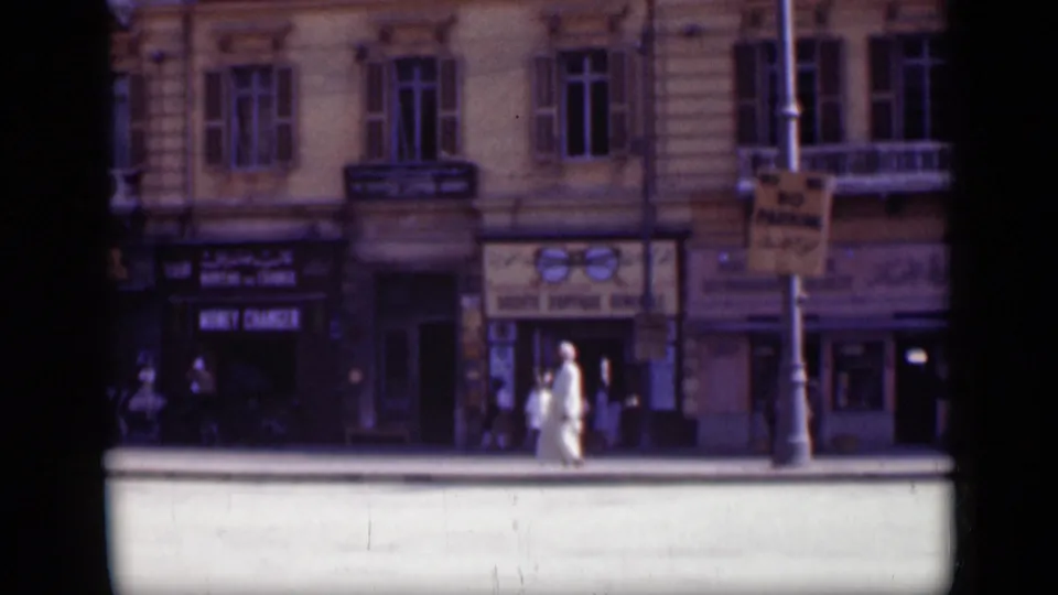 1946 Cairo street scene with a light-clothed pedestrian near shop entrances and commercial signs.