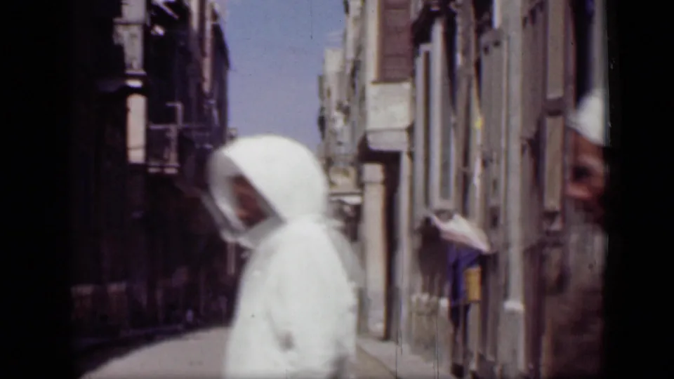 1946 Cairo street view with a person in white passing near the camera and pedestrians farther down a narrow sunlit lane.