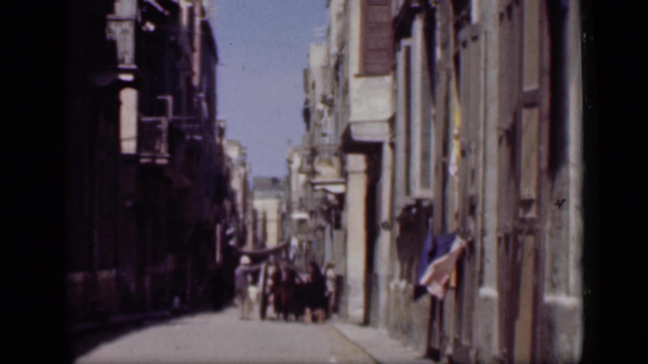 Narrow street with pedestrians walking in the distance between tall building facades.