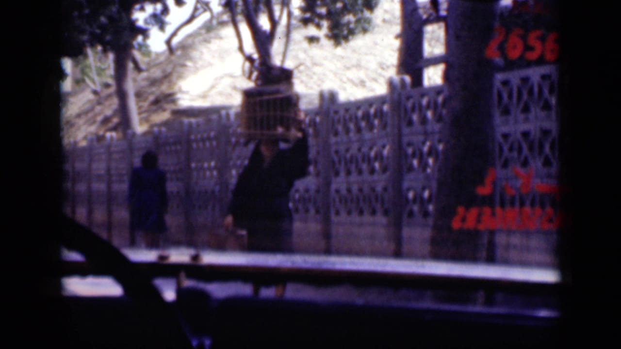 1946 Cairo street-side frame with people near a railing, trees above, and red painted lettering visible along the right edge.
