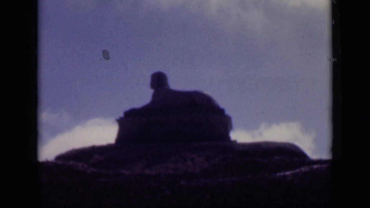 Sphinx-shaped silhouette centered against a pale blue sky with clouds near the horizon.