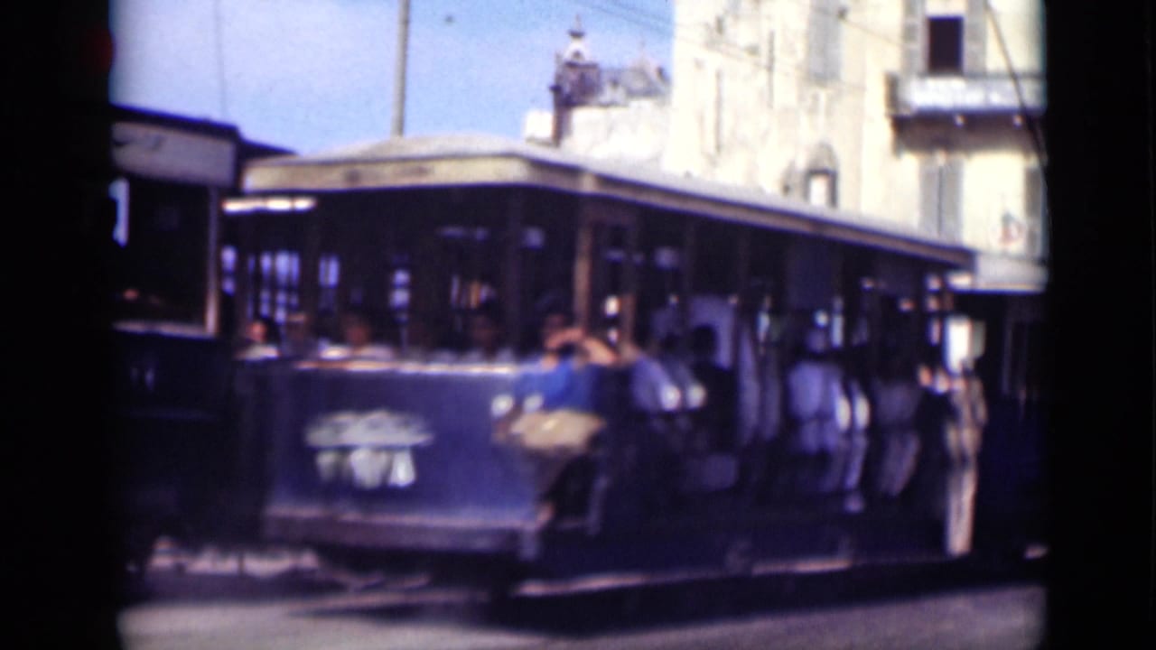 1946 Cairo footage shows a trolley car carrying passengers past pale masonry buildings on a bright street.