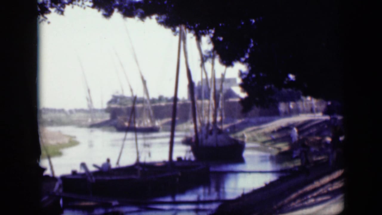 1946 Cairo riverbank view with traditional sailboats moored in shade and distant waterfront masonry across the water.