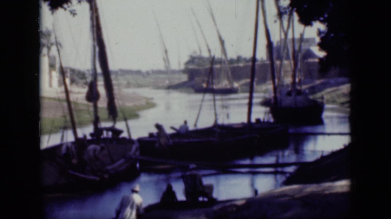 Canal scene with moored sailing boats, rigging, and small figures near the bank.