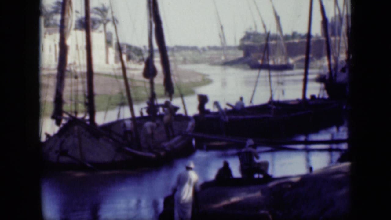 1946 Cairo canal scene with men near the bank, moored wooden sailing boats, rigging, tree shade, and bright water beyond.