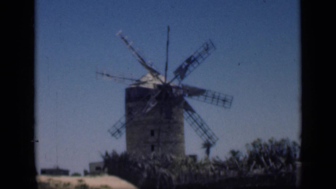1946 Cairo home-movie frame showing the windmill from a steady visitor viewpoint, with vegetation and sandy ground below.