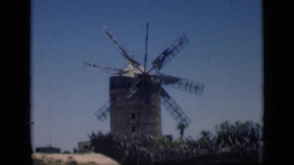 1946 Cairo home-movie frame showing the windmill from a steady visitor viewpoint, with vegetation and sandy ground below.