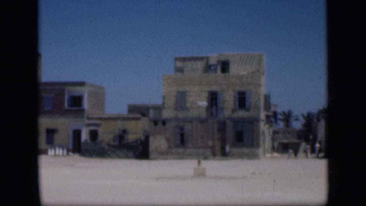 Old stucco buildings beside an open square, with a small distant figure near the right edge.