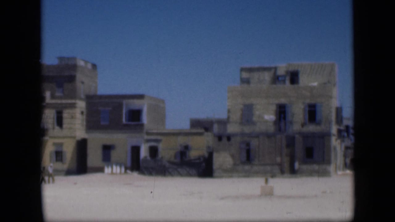1946 Cairo frame showing adjoining weathered buildings, a bright open square, dark window openings, and sparse details near the building fronts.