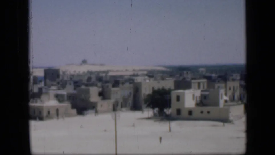 1946 Cairo view with clustered pale buildings, sparse trees, open sandy ground, and small distant pedestrians.