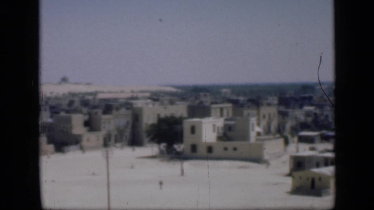 1946 Cairo travel footage looking over whitewashed buildings, flat roofs, a sandy street and distant low skyline.