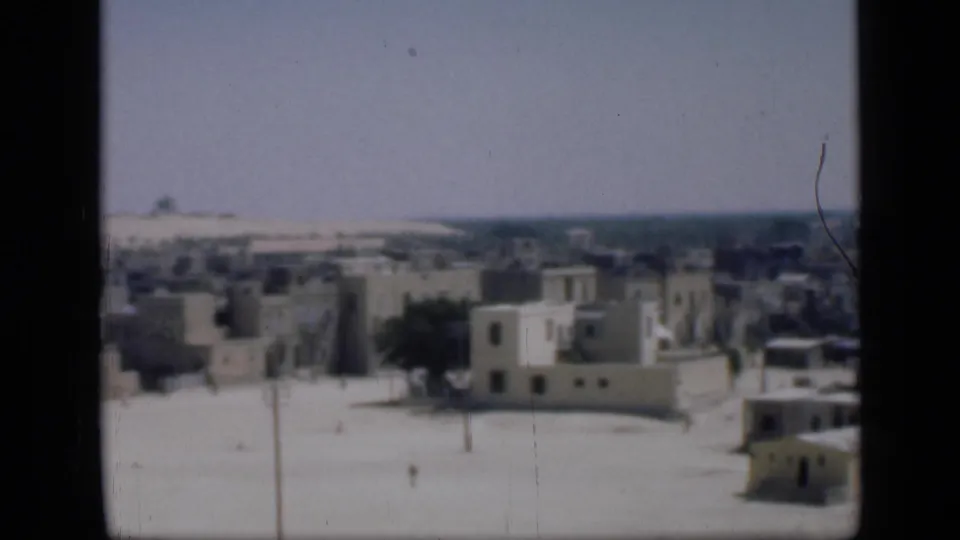 1946 Cairo travel footage looking over whitewashed buildings, flat roofs, a sandy street and distant low skyline.