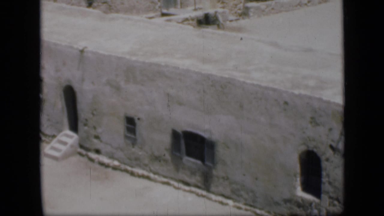Closer 1946 Cairo view of a weathered pale building with arched entrances, small windows and flat roof edges.