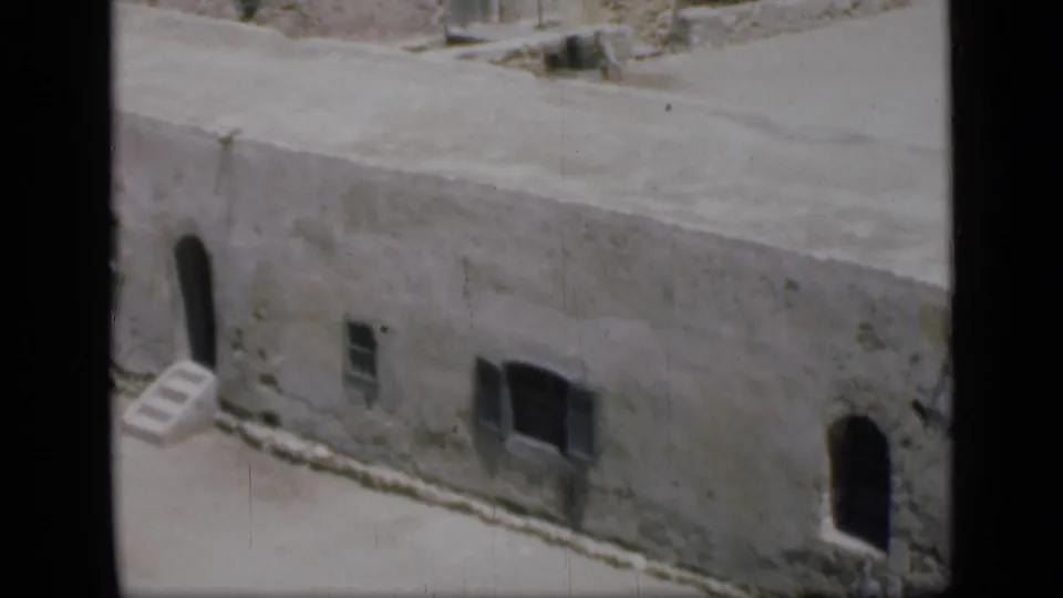 Closer 1946 Cairo view of a weathered pale building with arched entrances, small windows and flat roof edges.