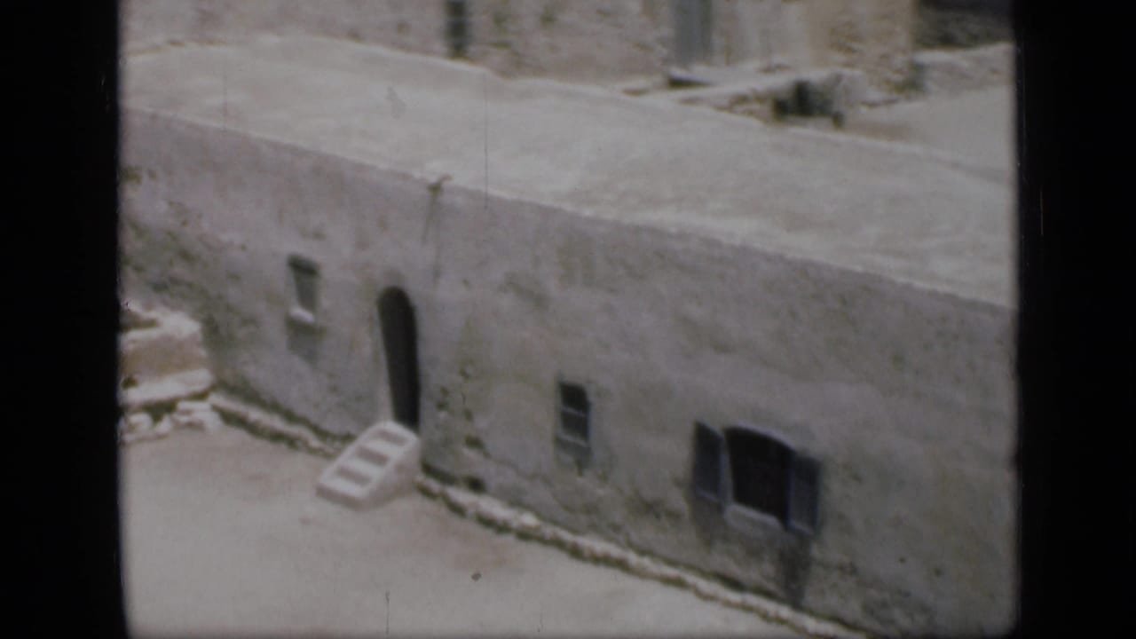 1946 Cairo travel frame showing a weathered flat-roofed building, arched doorway, small windows and sandy exterior space.