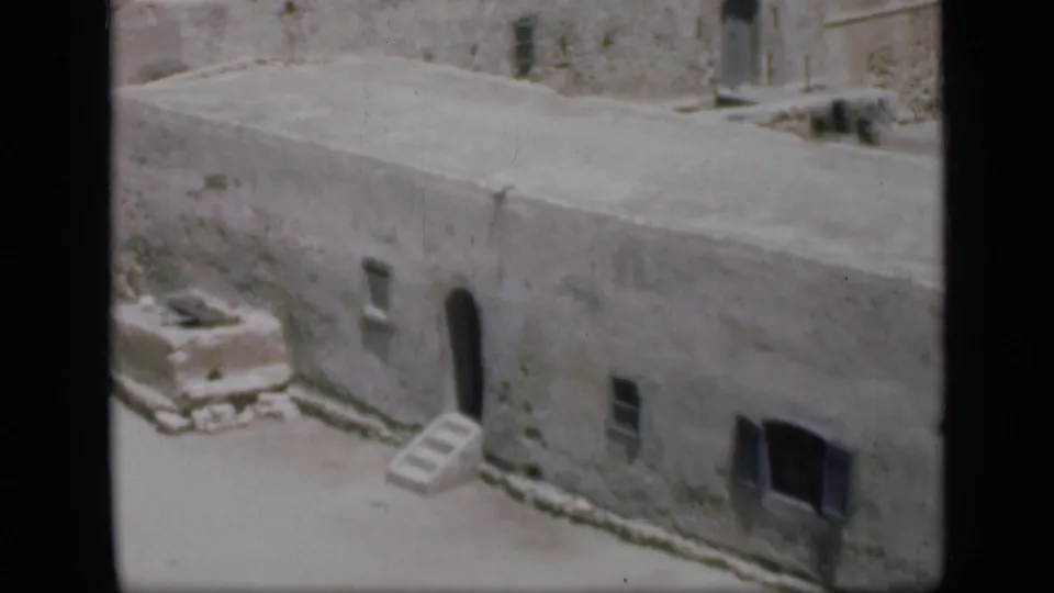 1946 Egypt 8mm frame showing a weathered stone structure with flat roof, small openings, steps, and an arched doorway.