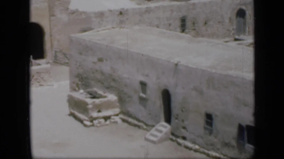 1946 Egypt 8mm frame of a pale stone building facade with an arched entrance, small window, and steps in harsh sunlight.