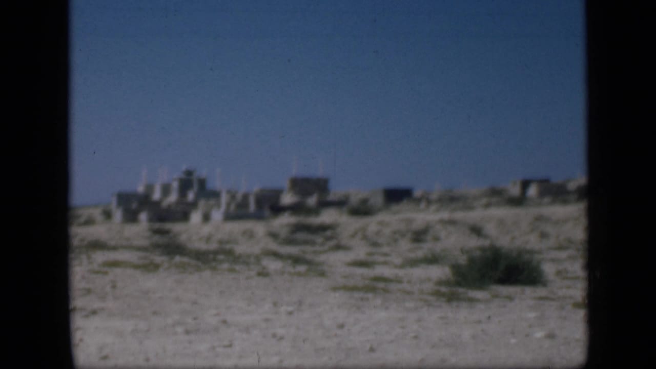 1946 Cairo-area view of low stone structures across sandy terrain with sparse vegetation and clear sky.