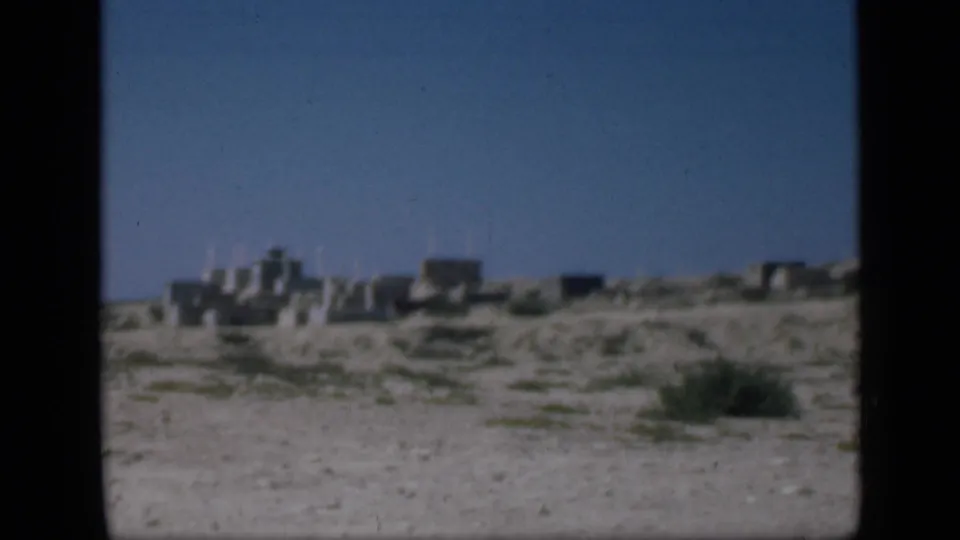 1946 Cairo-area view of low stone structures across sandy terrain with sparse vegetation and clear sky.