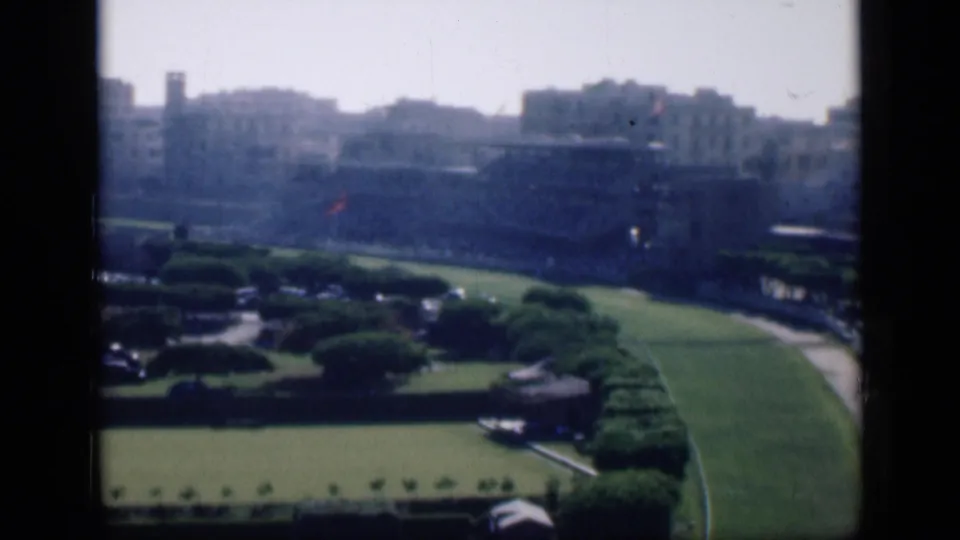 1946 Cairo home-movie view of a formal green park with lawns, trees, paths, and distant city buildings.