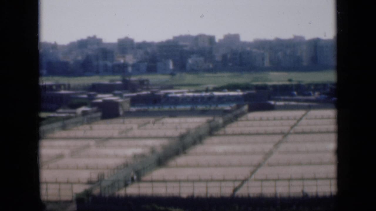 1946 Cairo panorama frame showing a gridded concrete storage area, low structures, green land and distant buildings.
