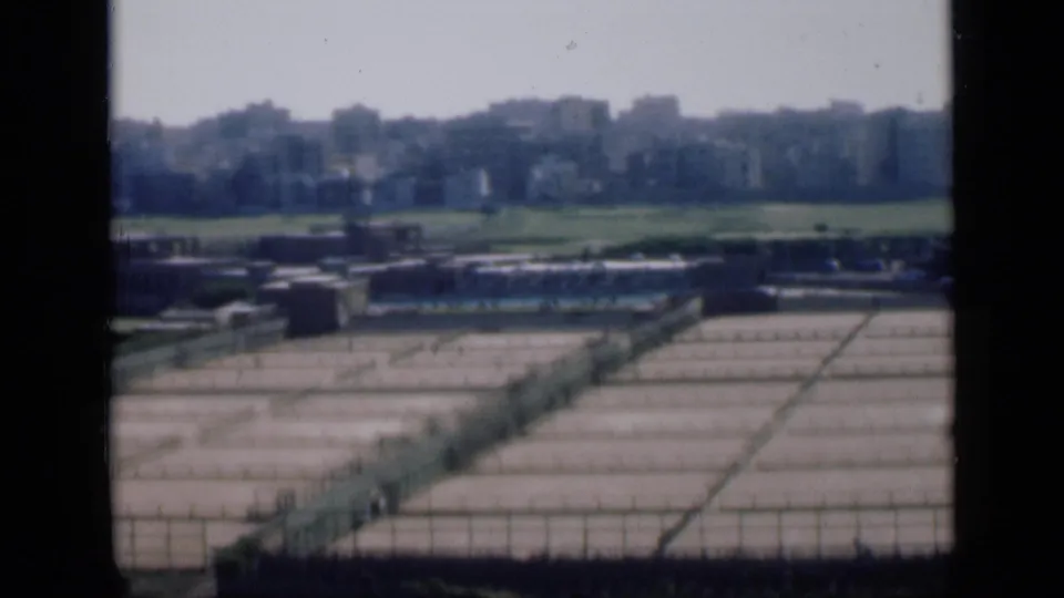 1946 Cairo panorama frame showing a gridded concrete storage area, low structures, green land and distant buildings.