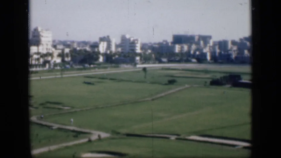 1946 Cairo view across open lawns and paths toward mid-century buildings, partly divided by a dark window mullion.