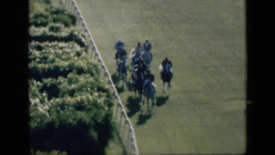 1946 Cairo horse race frame showing riders bunched near the inside rail as a dark horse runs wider on the grass.
