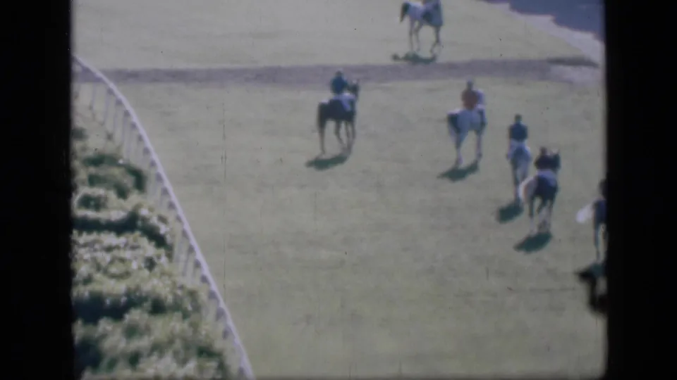 1946 Cairo racetrack view with multiple riders on horseback spread across the grass beside a white boundary rail.
