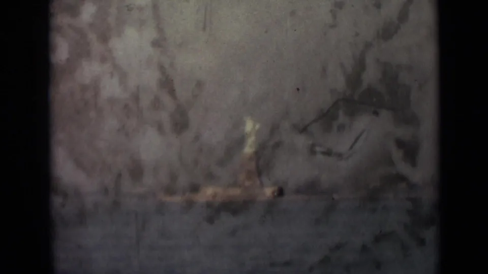 The distant Statue of Liberty is visible through heavier film abrasion, with the pedestal near the waterline and dark gate borders around the frame.