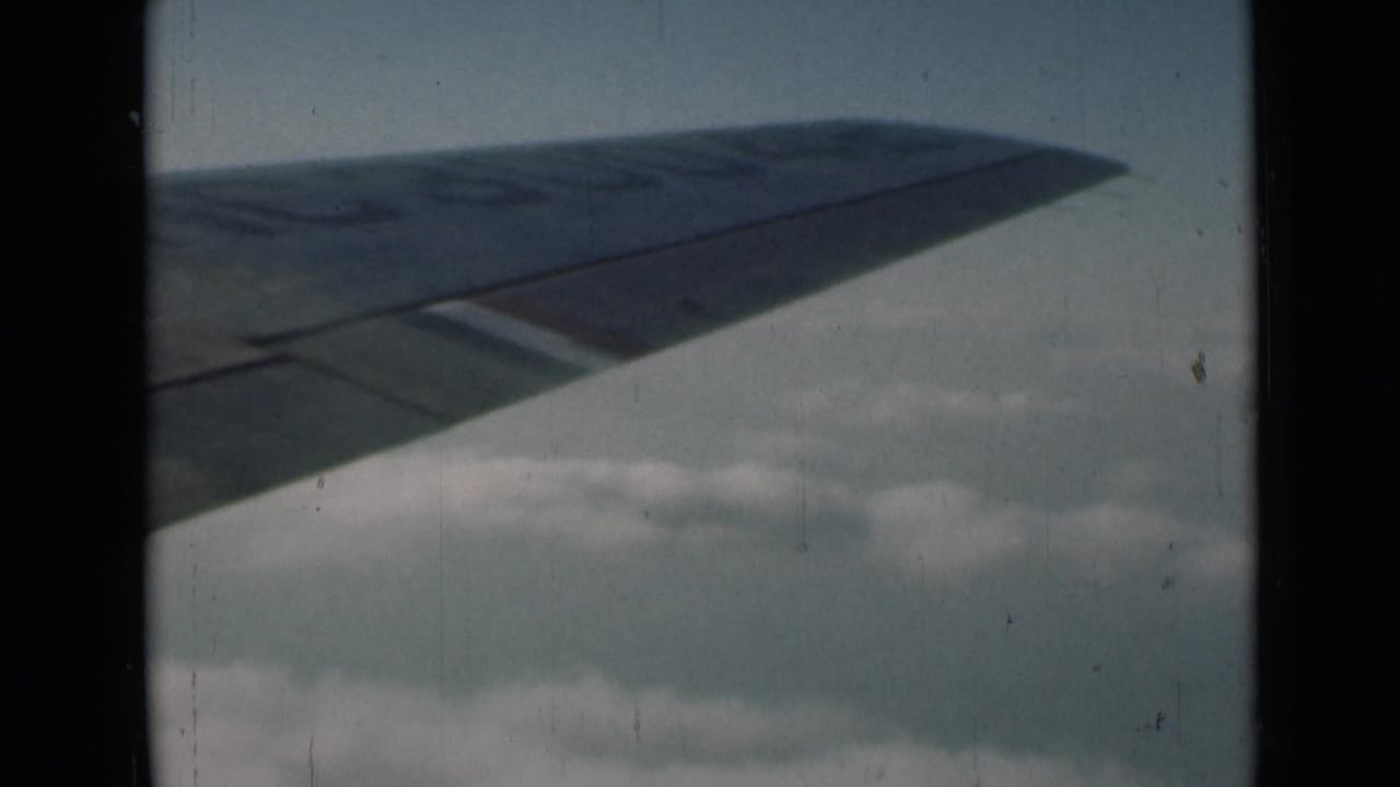 Airplane wing crossing the upper frame above a soft cloud bank.