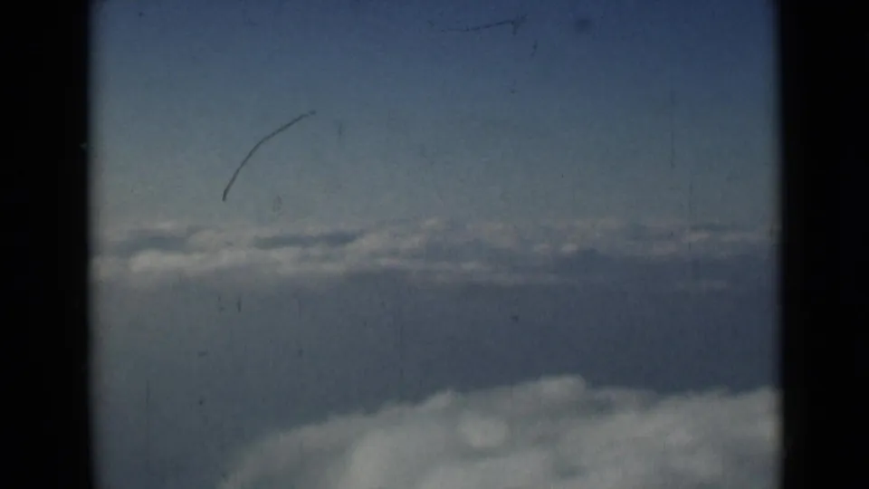 8mm frame of blue sky and soft cloud forms, attributed to London in 1946, with scratches and faded color visible.