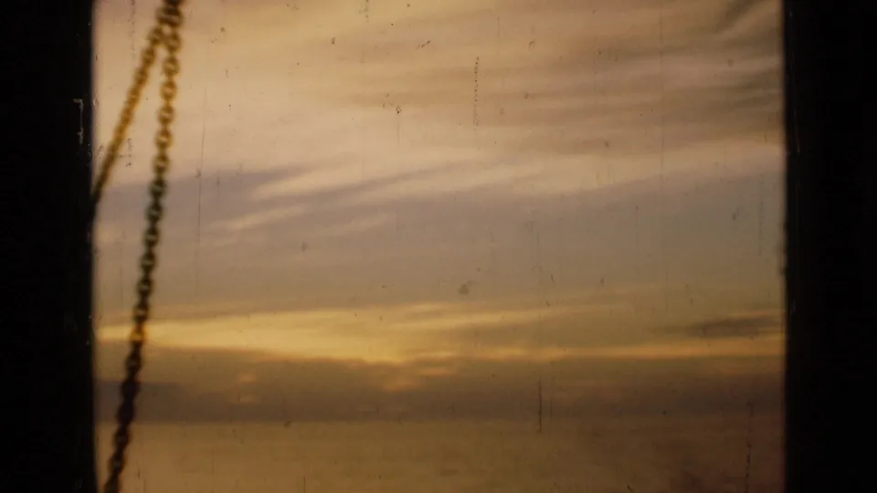 A warm sunset over water appears behind a hanging chain, likely another 1946 travel home-movie view.