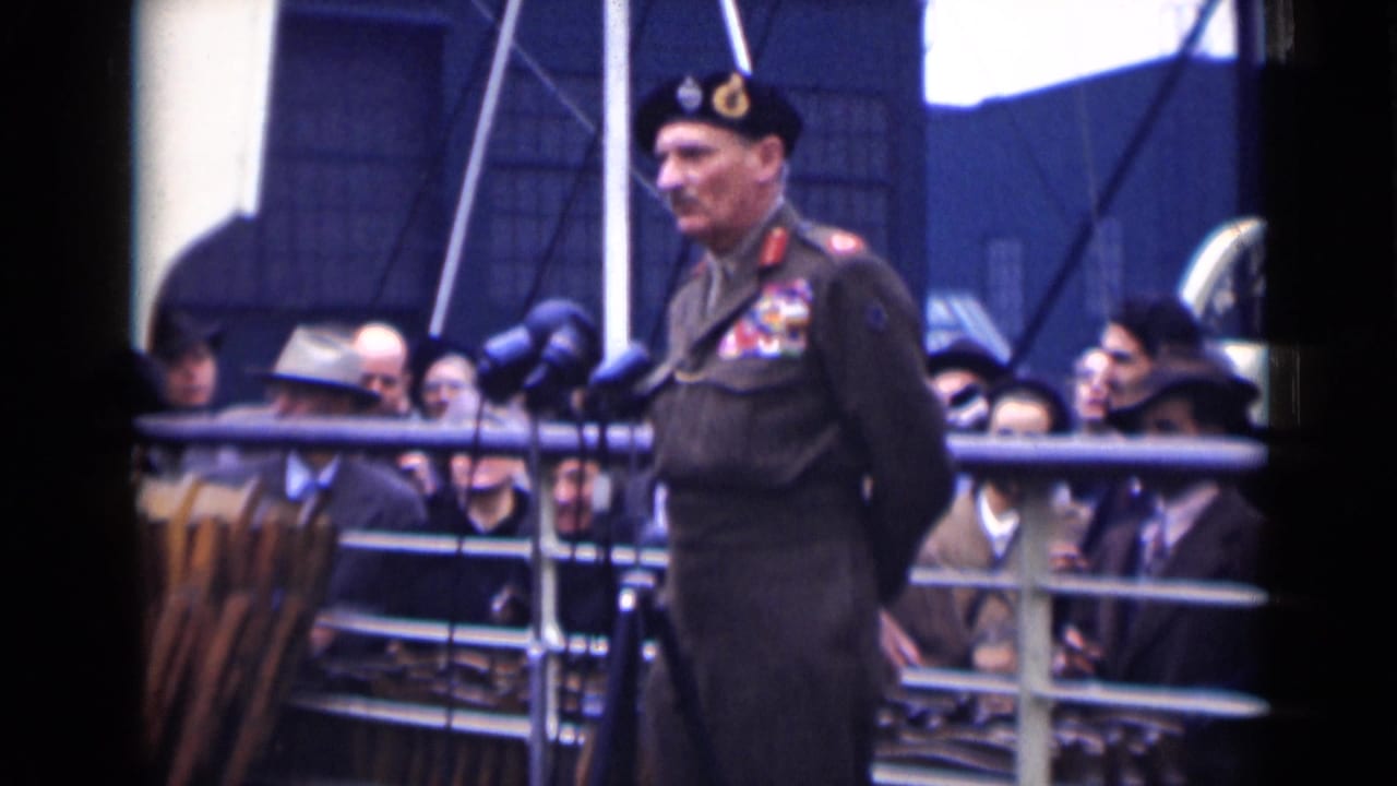 In London 1946 footage, a uniformed man with medals stands at clustered microphones while civilians watch from behind a metal railing.