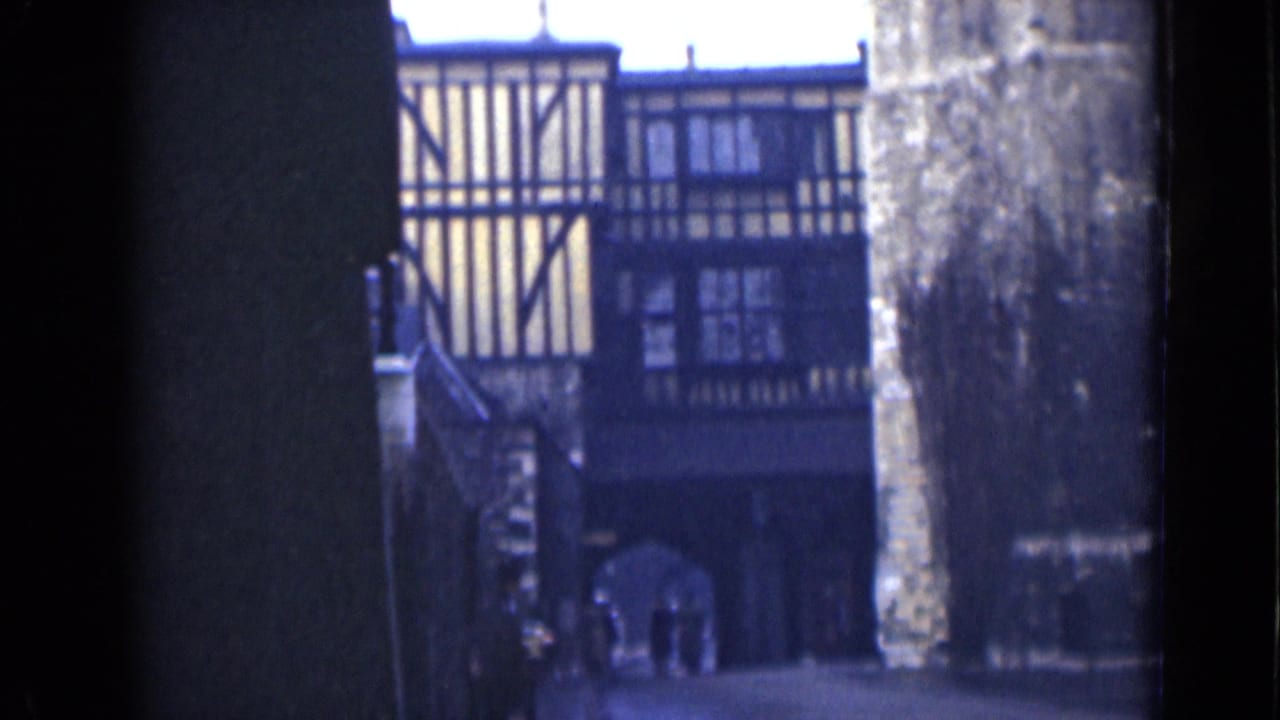1946 London frame of a historic-looking timber-framed facade, stonework, and pedestrians near an arched passage.