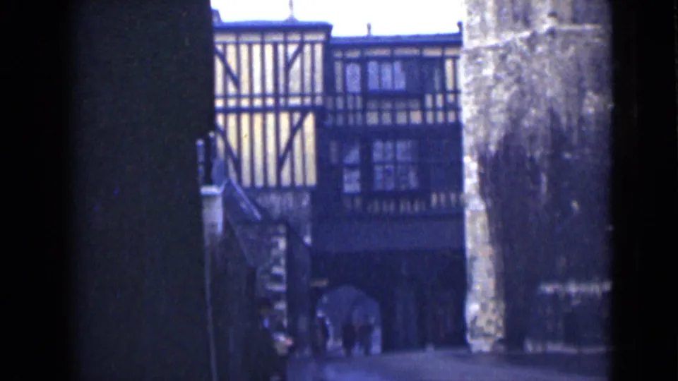 London 1946 8mm frame showing a timbered upper story above an archway, with small figures in the passage area.