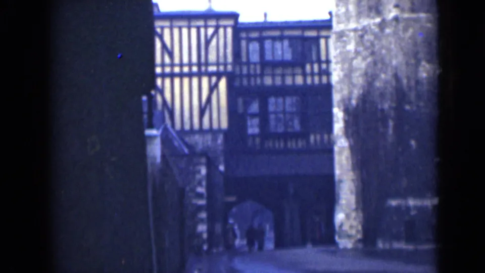 End frame from 1946 London footage showing the half-timbered facade and shadowed arch with indistinct pedestrians.