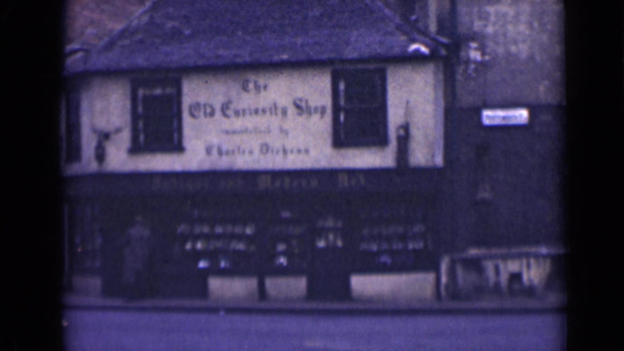 Old Curiosity Shop facade with painted sign, upper windows, dark storefront, and street pavement.