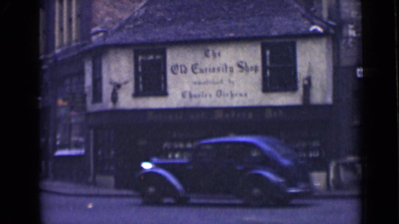 1946 London street view with a black vintage car moving past The Old Curiosity Shop exterior.